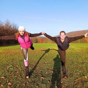 Dvě ženy ve skákacích botách cvičí venku na podzimní louce